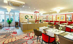 Interiör av en matsal med dukade bord och en buffé i bakgrunden. (AI-genererad text)