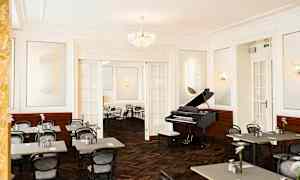 Ett elegant inrett rum med ett piano och uppställda cafébord och stolar. (AI-genererad text)