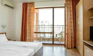 Ett hotellrum med en säng och en balkong med stolar. (AI-genererad text)