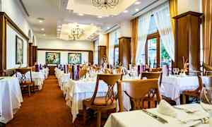 Interiör av en restaurang med dukade bord och stolar, ljusa gardiner och dekorativa taklampor. (AI-genererad text)