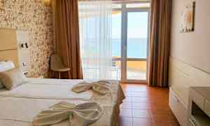 Ett hotellrum med en dubbelsäng bäddad med vita lakan och dekorerad med handdukar. Det finns ett fönster med utsikt mot havet. (AI-genererad text)