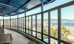 Interiör med en inglasad veranda som har utsikt över en stad och havet. (AI-genererad text)