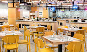 Bild av en matsal med träbord och gula stolar samt en buffé i bakgrunden. (AI-genererad text)