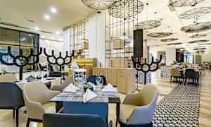 En modern restaurang med eleganta möbler och ett stilfullt tak. (AI-genererad text)