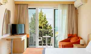 Ett hotellrum med balkong, säng, fåtölj och TV. (AI-genererad text)