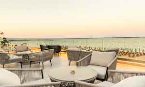 Utsikt över möblerad terrass med sittplatser och hav i bakgrunden. (AI-genererad text)