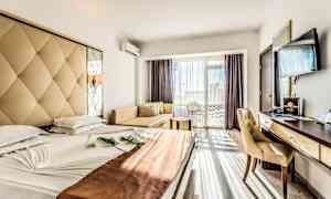 Ett hotellrum med en bred säng, ett skrivbord, en stol, en soffa och en TV. Rummet har stora fönster med utsikt. (AI-genererad text)