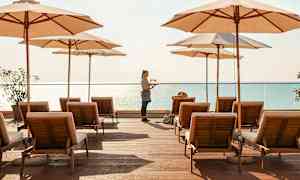 Solstolar och parasoller på en träplattform vid havet. (AI-genererad text)