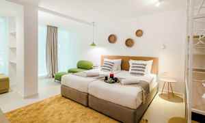 Ett modernt hotellrum med två enkelsängar, grön sittmöbel och dekorationer på väggen. (AI-genererad text)