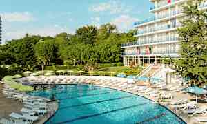 En pool omgiven av solstolar och parasoller nära ett hotell med flera våningar. (AI-genererad text)