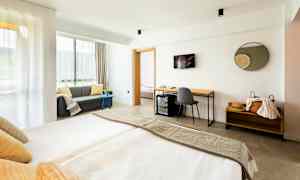 Modernt hotellrum med dubbelsäng, soffa och skrivbord. (AI-genererad text)