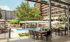 Utomhusområde vid hotell med en pool och sittplatser under tak. (AI-genererad text)