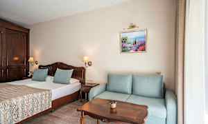 Rum med dubbelsäng, soffa, träbord och väggdekoration. (AI-genererad text)