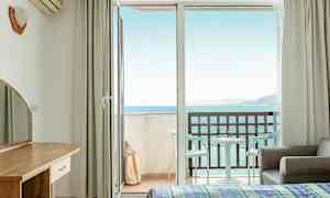 Hotelrum med öppen balkongdörr och havsutsikt. (AI-genererad text)