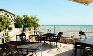 Uteservering med utsikt över havet och kustlandskap. (AI-genererad text)