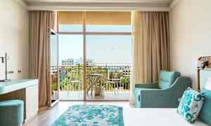 Hotellrum med dubbelsäng, turkos inredning och balkong med utsikt. (AI-genererad text)