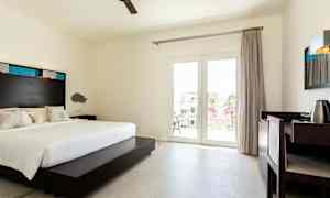 Ett hotellrum med en dubbelsäng, skrivbord och balkongdörrar. (AI-genererad text)