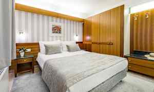 Ett hotellrum med en bäddad säng, träinredning och väggkonst. (AI-genererad text)