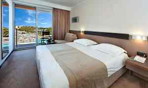 Ett hotellrum med en dubbelsäng, sittområde och en terrass med utsikt. (AI-genererad text)