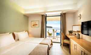 Ett hotellrum med två enkelsängar, en balkong med havsutsikt och en sittgrupp. (AI-genererad text)