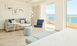 Ljust och modernt hotellrum med sittgrupp och utsikt mot havet. (AI-genererad text)