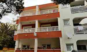 Flerfamiljshus med balkonger och fönster, omgärdat av växter. (AI-genererad text)