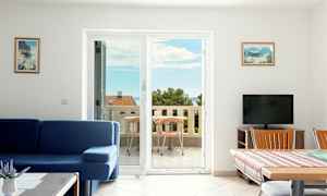 Vardagsrum med blå soffa och matbord bredvid en balkong med havsutsikt. (AI-genererad text)