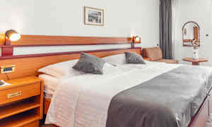 Hotellrum med stor säng, sidobord och dekorationer. (AI-genererad text)