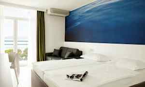 Dubbelrum med stor blå väggmålning bakom sängen. Balkong med havsutsikt. (AI-genererad text)