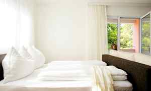 Ett ljust rum med en säng nära fönster och balkong. (AI-genererad text)