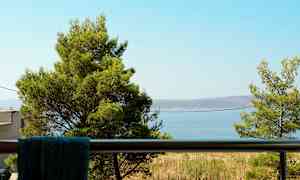 Utsikt från en balkong med träd och havet i bakgrunden. (AI-genererad text)