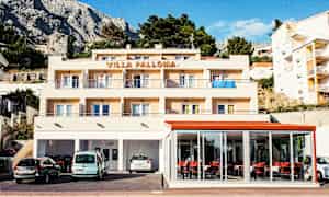 En byggnad med texten 'Villa Palloma' på toppen, med balkonger och parkerade bilar framför. (AI-genererad text)