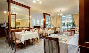 Restaurang med dukade bord och stolar inomhus. (AI-genererad text)