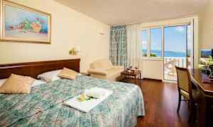 Hotellrum med dubbelsäng och balkong med havsutsikt. (AI-genererad text)