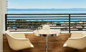 Utsikt över havet från en balkong med sittplatser och ett bord. (AI-genererad text)