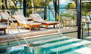 Solstolar vid en pool med utsikt mot havet. (AI-genererad text)