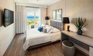 Hotellrum med dubbelsäng och utsikt över havet. (AI-genererad text)