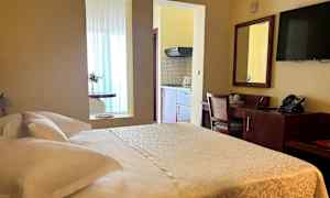 Foto av ett hotellrum med en dubbelsäng, skrivbord och en kökshörna. (AI-genererad text)