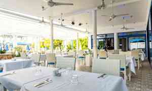 Uteservering med bord dukade med vita dukar. (AI-genererad text)