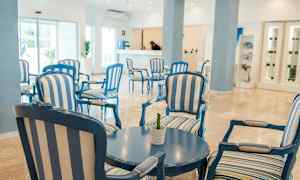 Ett ljust och luftigt hotellfoajé med blåa och vitrandiga sittmöbler och ett runt bord. (AI-genererad text)