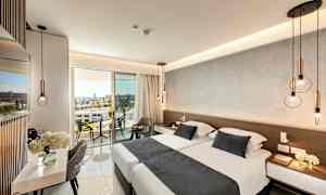 Modernt inrett hotellrum med dubbelsäng, sittmöbler och en balkong med utsikt. (AI-genererad text)