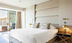 Modernt hotellrum med stor säng, elegant inredning och utsikt mot en terrass. (AI-genererad text)