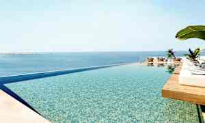 En infinitypool med utsikt över havet och solstolar omkring. (AI-genererad text)