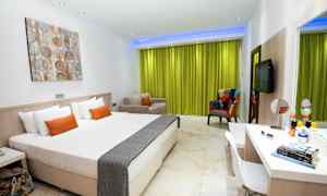 Ett modernt hotellrum med vit inredning och grön gardin. (AI-genererad text)