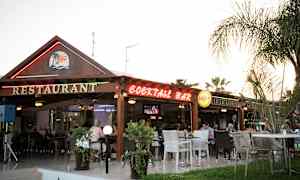 En restaurang och cocktailbar med utomhusservering belägen i en trädgård. (AI-genererad text)