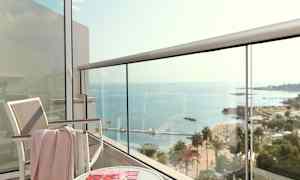 Utsikt från en balkong mot havet, med en stol, ett bord och ett magasintidning. (AI-genererad text)