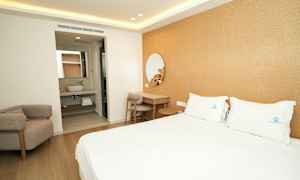 Ett hotellrum med en dubbelsäng, ett skrivbord och en armstol. I bakgrunden syns ett badrum. (AI-genererad text)