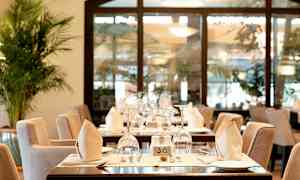 Ett restaurangbord med elegant dukning som inkluderar glas, tallrikar och vikta servetter. (AI-genererad text)