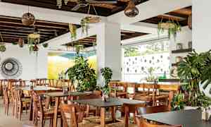 Restaurang med träbord och stolar, dekorerad med gröna växter. (AI-genererad text)