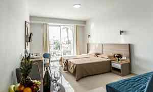 Ett hotellrum med dubbelsäng, sittgrupp och en terrass utanför. (AI-genererad text)